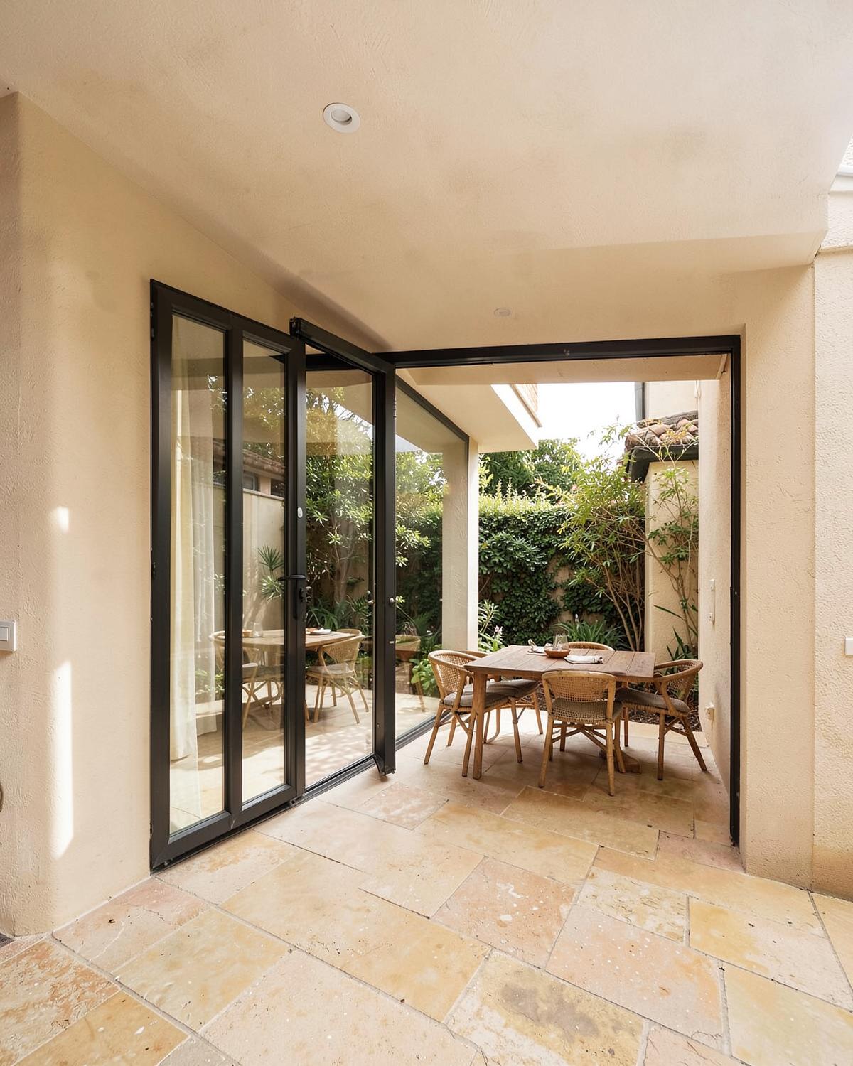 Rear home extension with folding glass doors opening onto a paved garden terrace